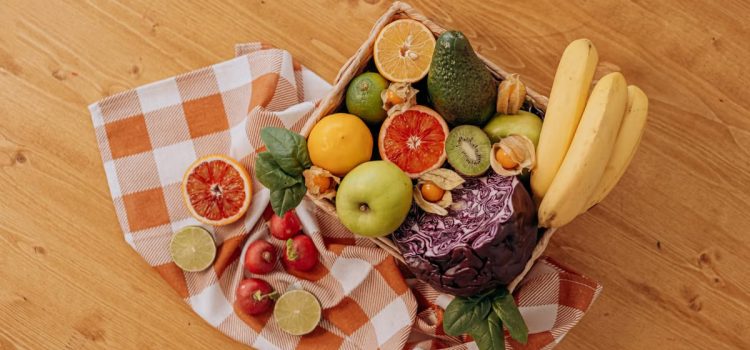 Alimenti essenziali per una nutrizione equilibrata A vibrant flat lay of assorted fresh fruits on a checkered cloth over a wooden surface, perfect for healthy lifestyle concepts.
